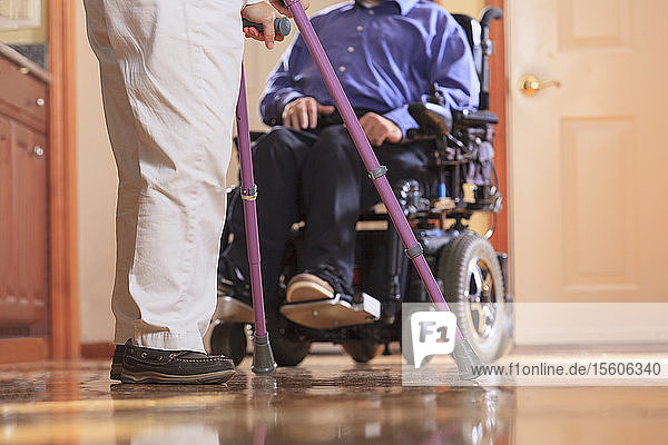 Frau mit Cerebralparese an Krücken und ihr Mann mit Cerebralparese in einem motorisierten Rollstuhl