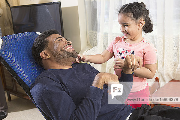 Afroamerikanischer Mann mit Cerebralparese hat Spaß mit seiner Tochter zu Hause Cerebralparese