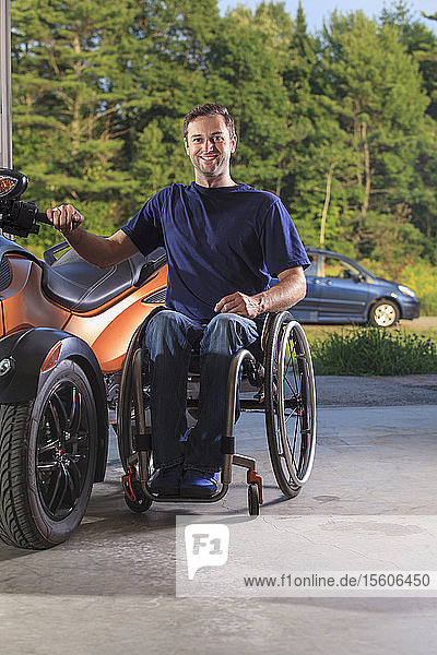 Man with spinal cord injury sitting in wheelchair beside his custom motorcycle
