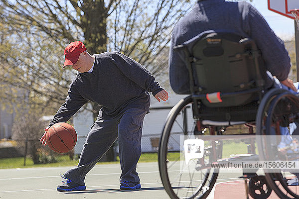 Ein Vater mit einer Rückenmarksverletzung und sein Sohn mit Down-Syndrom spielen Basketball in einem Park