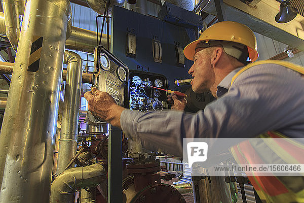 Engineer in electric power plant inspecting sensor with flash light