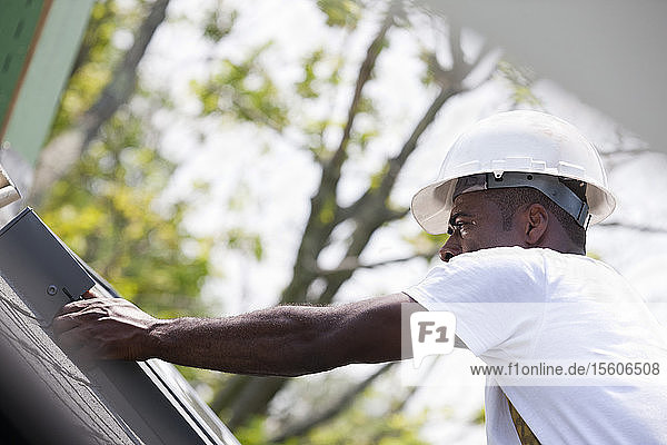Zimmermann beim Anbringen der Eindeckrahmen um das Dachfenster auf dem Dach