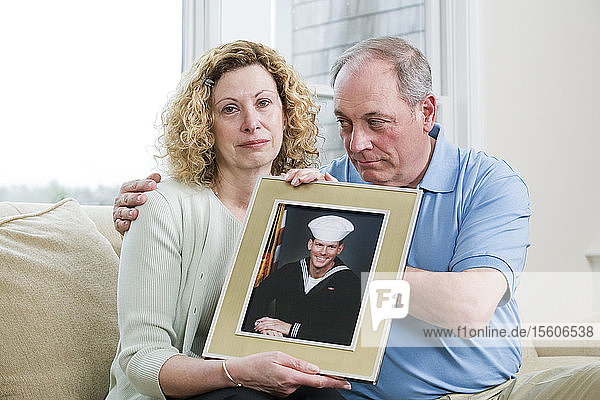 Porträt eines reifen Paares  das ein Bild seines Sohnes hält  der beim Militär arbeitet