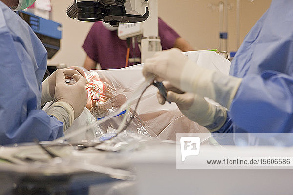Chirurgische Technikerin mit Phako-Instrument und Arzt mit einer Spritze