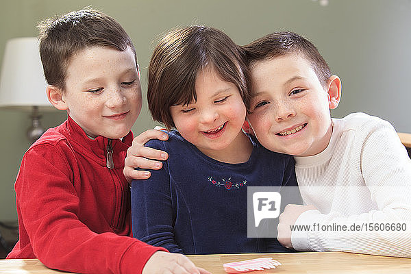 Kleines Mädchen mit Down-Syndrom spielt mit ihren Brüdern