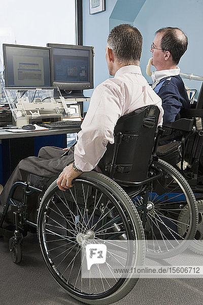 Zwei Geschäftsleute im Rollstuhl arbeiten in einem Büro