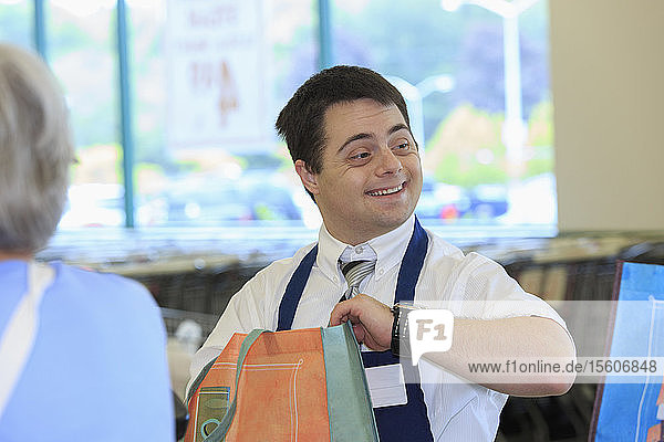 Man with Down Syndrome working at a grocery store with a customer