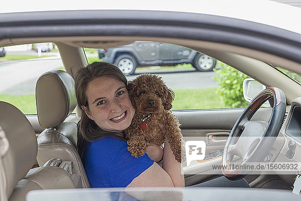Junge Frau mit zerebraler Lähmung hält ihren Hund im Auto