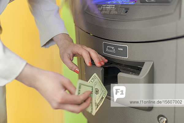 Junge blinde Frau  die an einem Bankautomaten Geld abhebt