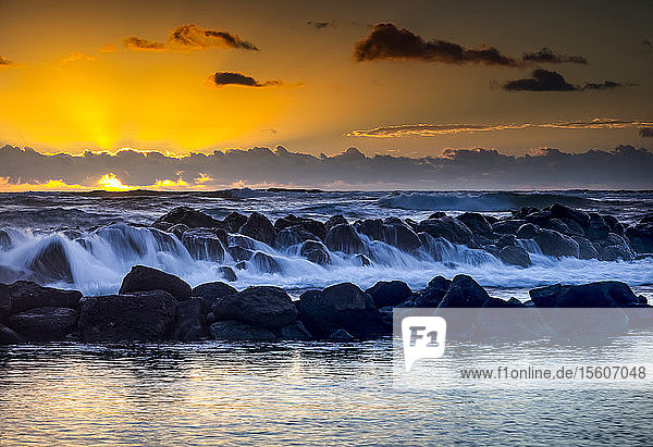 Goldener Sonnenaufgang über dem Lydgate Park und dem Ozean an der Küste von Kauai mit einem silhouettierten Wellenbrecher; Kapaa  Kauai  Hawaii  Vereinigte Staaten von Amerika
