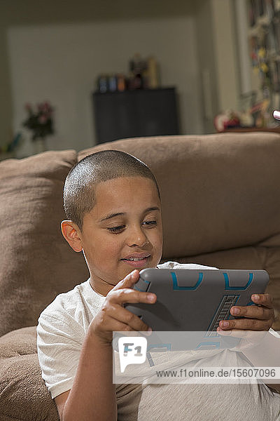 Hispanischer Junge mit Autismus spielt zu Hause ein elektronisches Spiel