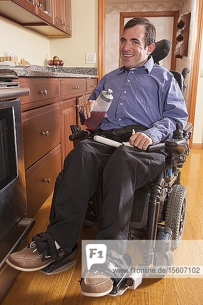 Mann mit zerebraler Lähmung in der Küche seines Hauses beim Mittagessen