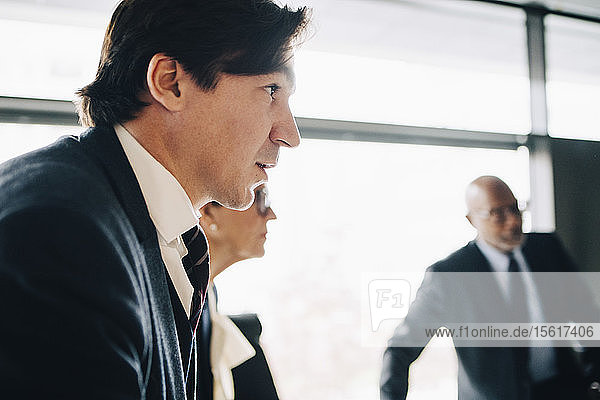 Geschäftsmann schaut weg  während er mit Kollegen bei einer Besprechung im Büro steht