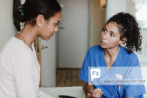 Ärztin diskutiert mit Patientin im Krankenzimmer im Krankenhaus
