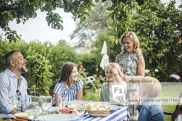 Family having fun at dining table in garden party during summer weekend