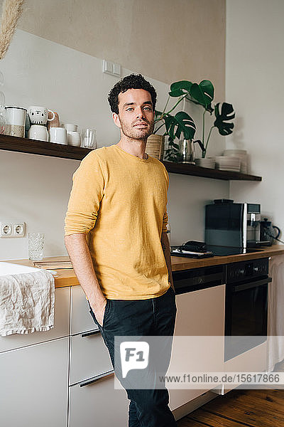 Porträt eines selbstbewussten Mannes mittleren Alters  der zu Hause in der Küche steht