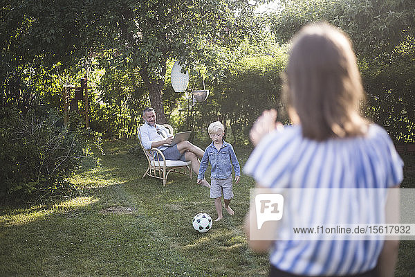 Vater sieht Sohn beim Fussballspielen mit Tochter im Garten