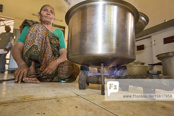 Der Muni Seva Ashram in Goraj  in der Nähe von Vadodara  Indien  ist eine ruhige Oase der humanitären Fürsorge. Der Ashram ist äußerst nachhaltig und wird nächstes Jahr völlig kohlenstoffneutral sein. Die ersten Sonnenkollektoren wurden 1984 installiert  lange bevor der Klimawandel auf der Tagesordnung stand. Die Energieversorgung erfolgt über Sonnenkollektoren und Holz  das auf dem Gelände angebaut wird. Lebensmittelabfälle und tierische Exkremente werden in Biogas umgewandelt  mit dem die Autos des Anwesens betrieben und auch zum Kochen verwendet werden. Außerdem werden Solarkocher verwendet  und die Klimaanlage des Krankenhauses wird mit Solarenergie betrieben. 70 % der verwendeten Lebensmittel werden auf dem Landgut angebaut. Es gibt ein Waisenhaus  Schulen für alle Altersgruppen  Berufsausbildung  Altenpflege  ein spezialisiertes Krebskrankenhaus mit hochmodernen Maschinen und sogar ein solarbetriebenes Krematorium. Diese Aufnahme zeigt das Personal in der Küche des Altenheims  das mit auf dem Gelände erzeugtem Biogas kocht.
