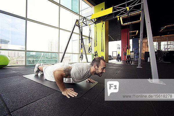 cross-training  muscular man doing push ups in gym