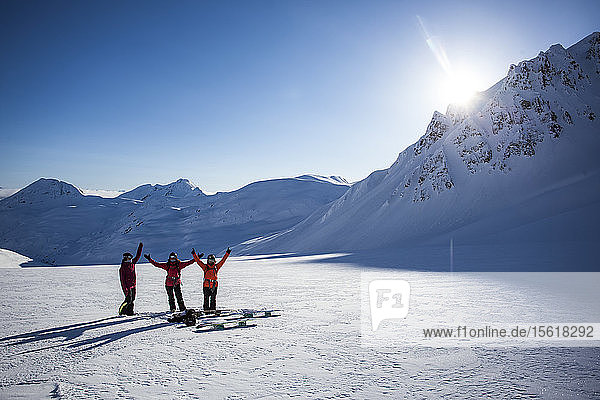 Professional snowboarders  Robin Van Gyn  Marie France Roy  and Helen Schettini throw their hands up in excitement after a fun run on a sunny day in Haines  Alaska.