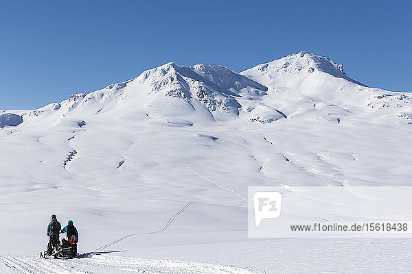 Snowboarder mit ihrem Schneemobil beim Wandern im Norden von British Columbia