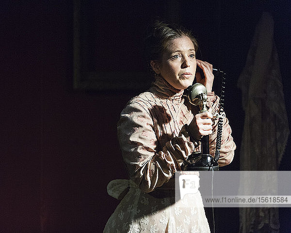 Eine Frau spricht in ein altes Telefon.