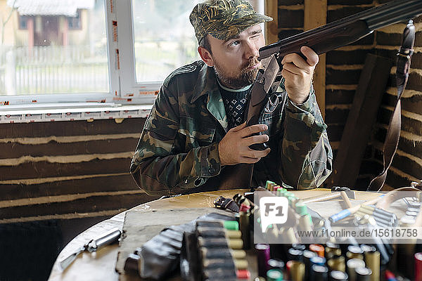 Vorderansicht eines Mannes  der bei den Vorbereitungen für einen Jagdausflug das Visier seiner Flinte überprüft  Tichwin  Sankt Petersburg  Russland