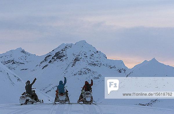 Drei Snowboarder mit Motorschlitten geben Daumen hoch Zeichen  wie sie übersehen fernen Bergen