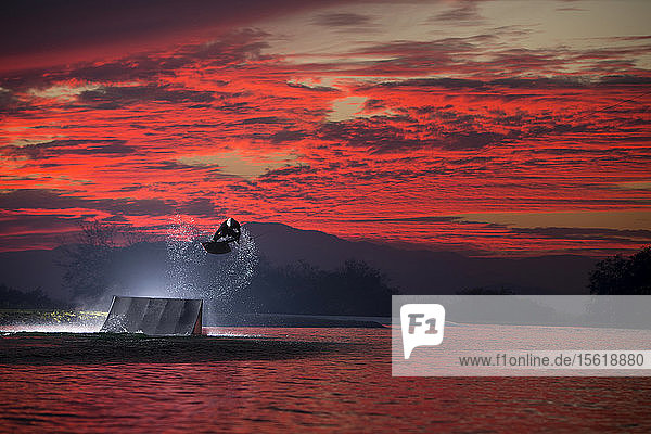 Wakeboarder beim Sprung gegen den dramatischen roten Himmel in der Abenddämmerung  Tequesquitengo  Morelos  Mexiko