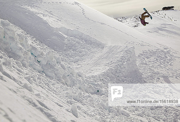 Ein Snowboarder schlägt einen Sprung und macht einen Backflip am Cerro Catedral in Argentinien