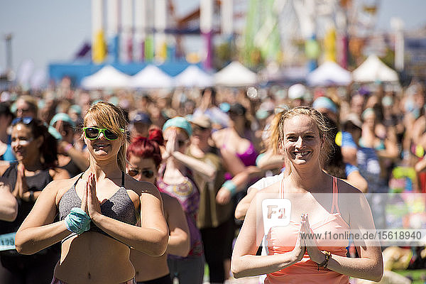 People doing hands to heart during outdoor yoga festival on Santa Monica Pier in Santa Monica  California  USA