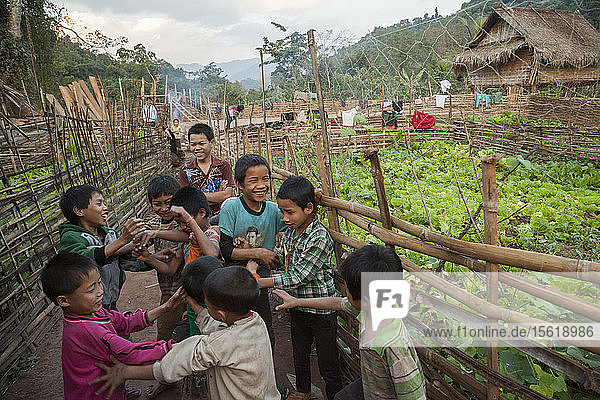 Jungen spielen in der Gasse zwischen zwei Gartenzäunen in Muang Hat Hin  Laos.