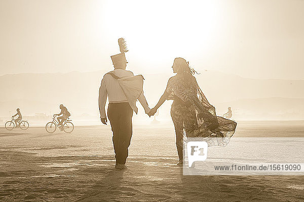 Ein Paar geht beim Burning Man in die untergehende Sonne.