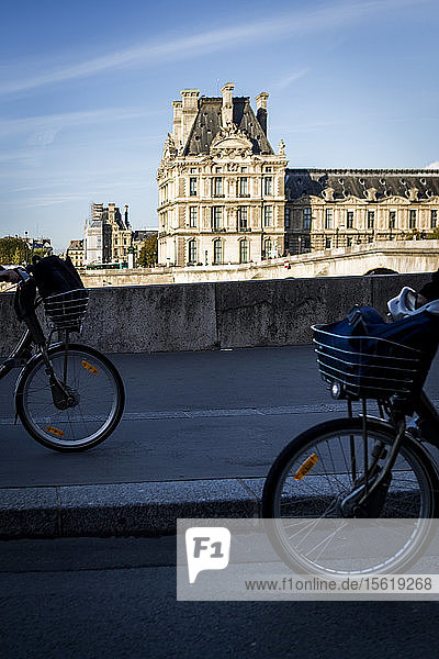 Zwei Fahrräder kreuzen sich auf einem Pariser Bürgersteig.