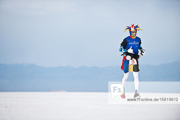 Ein als Narr verkleideter männlicher Athlet läuft während des Salt Flats 100 in Bonneville  Utah  über die Bonneville Salt Flats.