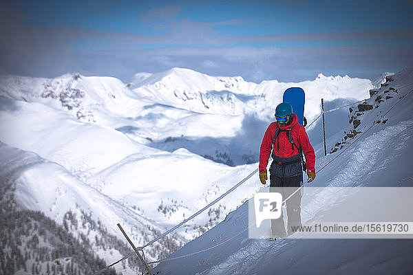 A snowboarder traverses a narrow ledge on top of Silverton Mountain in Colorado.