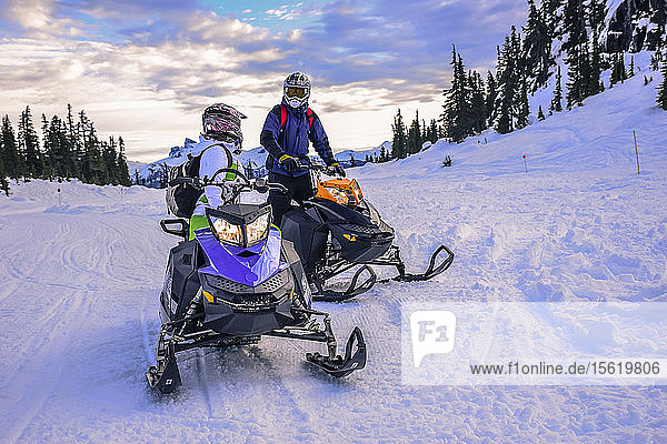 Zwei abenteuerlustige Menschen unterhalten sich beim Schneemobilfahren  Callaghan Valley  Whistler  British Columbia  Kanada