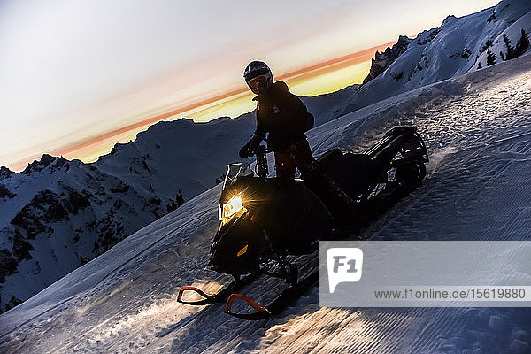 Single adventurous woman on snowmobile at sunset Callaghan Valley Whistler British Columbia Canada