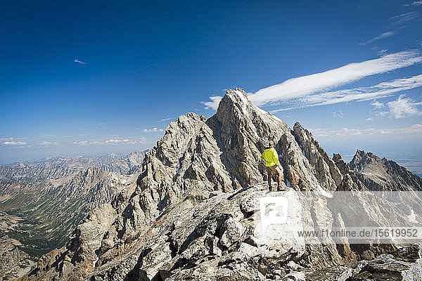 A Hiker Stands At The Top Of Rocky Mountain Exploring Grand Teton National Park
