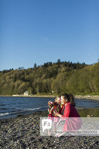 Mother and little daughter relaxing on rocky coastal beach  Seattle  Washington  USA