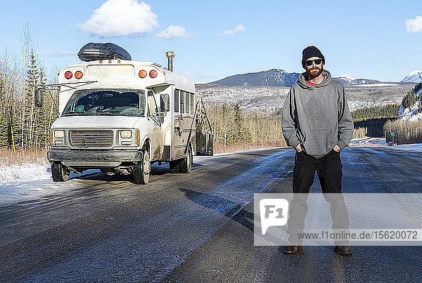 Mann in der Mitte des Alaska Highway stehend  während er nach Norden nach Alaska fährt