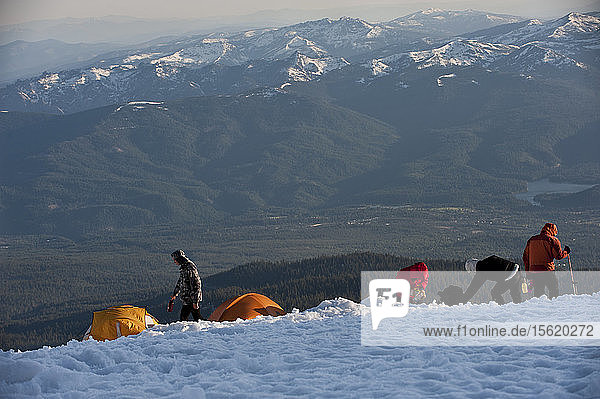 Jungen im Alter von 13 bis 17 Jahren von der Venturing Crew 191 aus Glendora  Kalifornien  setzen ein Jahr Training in die Praxis um  als sie versuchen  den Gipfel des Mount Shasta über die Avalanche Gulch-Route im Shasta Trinity National Forest in Nordkalifornien zu erreichen. Der Mount Shasta ist ein massiver  vergletscherter Vulkan und mit 14.179 Fuß der zweithöchste Gipfel in der Cascade Range und der fünfthöchste in Kalifornien; er ist mit keinem anderen Gipfel verbunden und erhebt sich abrupt 10.000 Fuß über das umliegende Gelände. Die Pfadfinder der Venturing Crew 191 (Venturing Crews sind ein Zweig der Pfadfinder  der sich auf abenteuerliche Aktivitäten konzentriert) hatten sich ein Jahr lang auf ihre Besteigung des Mount Shasta vorbereitet. Dies war ihre erste Erfahrung mit dem Klettern in steilem Schnee  und sie wurden bei ihrem Aufstieg von Führern der SWS Mountain Guides unterstützt. Josh Kolbach (links) von Venturing Crew 191 trägt im letzten Abendlicht eine Wasserflasche zurück zu seinem Zelt  während die Bergführer JB und Casey Hurden im Hochlager auf 10.000 Fuß am Mount Shasta die letzten Vorbereitungen treffen. Die Crew wird vor der Morgendämmerung aufbrechen  um den Gipfel des Mount Shasta über die Avalanche Gulch Route im Shasta Trinity National Forest  Kalifornien  zu erreichen.