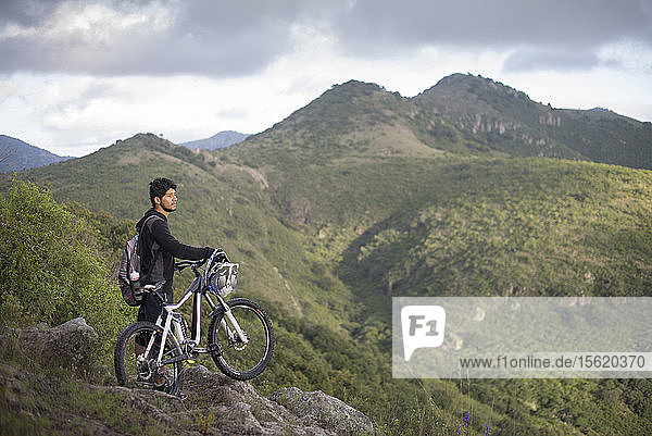 A mountain biker with his bike stears at the landscape during a trip at Joya La Barreta area in Queretaro  Mexico.