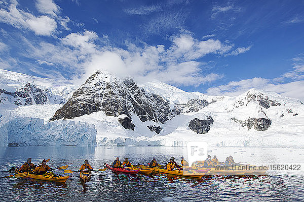 Members of an expedition cruise to Antarctica sea kayaking in Paradise Bay beneath Mount Walker on the Antarctic peninsula. The Antarctic peninsula is one of the most rapidly warming areas on the planet.