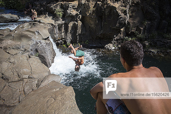 Young man cliff jumping near waterfall and another watching ï¾ McCloudï¾ River California USA