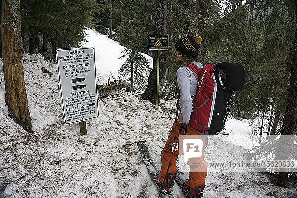 Man looks at avalanche control warning signs in backcountry