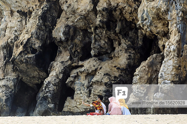 Kleine Gruppe von drei Personen  die am Strand vor einem Berg sitzen  Banda Aceh  Sumatra  Indonesien