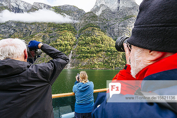 Schiffspassagiere fotografieren einen Wasserfall im Naeroyfjord  Sogn og Fjordane  Norwegen