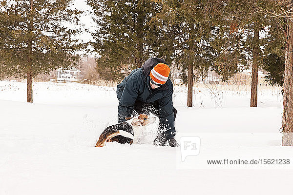 Mann beim Schneeschuhwandern im Wald mit seinem Beagle