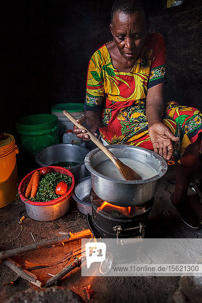 In ihrem Haus in der Nähe von Arusha  Tansania  bereitet die Solarunternehmerin Julieth Mollel ein Abendessen aus Ugali  Gemüse und Bohnen vor  das sie auf ihrem sauberen Kochherd zubereitet. Ugali ist ein Grundnahrungsmittel  das in vielen Ländern Afrikas gegessen wird  und besteht aus Maismehlbrei. Die nächtliche Arbeit in ihrer kompakten Außenküche wird durch den sauberen Herd erleichtert  der nur wenig Rauch entwickelt und nur einen Bruchteil des Brennholzes eines traditionellen Drei-Steine-Kochers benötigt. Julieth Mollel steht aufrecht da  wenn sie sagt  dass sie eine Solar Sister Entrepreneur ist  und ihr Erfolg beim Verkauf der Laternen und Kochherde hat ihr Hoffnung für ihre Zukunft und die ihrer Enkelkinder gegeben. Julieth Mollel hat kein einfaches Leben gehabt. Julieth und ihr Mann gehören dem Stamm der Massai an und leben im Norden Tansanias  etwa eine Stunde außerhalb von Arusha  an den Südhängen des Mount Meru. Julieth hat ihr ganzes Leben lang in der Landwirtschaft geschuftet  Ernten verkauft und den Haushalt für ihren Mann und ihre Kinder geführt. Jetzt  mit einundsechzig (61) Jahren  arbeitet sie hart  um die Familie zu ernähren und die Schulgebühren für ihre Enkelkinder zu bezahlen. Bis sie begann  für Solar Sister in Tansania zu arbeiten  war das Leben für Julieth fast unerträglich geworden. Beim Kochen auf ihrem traditionellen Herd  der aus drei Steinen und einer offenen Feuerstelle bestand  entstand viel Rauch  den sie einatmete  wenn sie das Frühstück  Mittag- und Abendessen für ihre Familie kochte. Der Herd benötigte viel Brennholz  so dass sie täglich hinausgehen und ein großes Bündel Holz nach Hause bringen musste. Mit der Zeit bekam sie starke Schmerzen in der Brust und hatte Schwierigkeiten  das Brennholz aufzulesen und nach Hause zu tragen. Im Laufe der Jahre musste Julieth immer weiter laufen  um Brennholz zu bekommen  weil in der Gegend Bäume gefällt wurden  um Farmen zu vergrößern und Siedlungen zu bauen  und weil Brennholz zum Kochen und zur Herstellung von Holzkohle gesammelt wurde. Während dieser Zeit kämpfte Julieth darum  das Schulgeld für ihre Enkelkinder zu bezahlen  aber es wurde immer schwieriger.